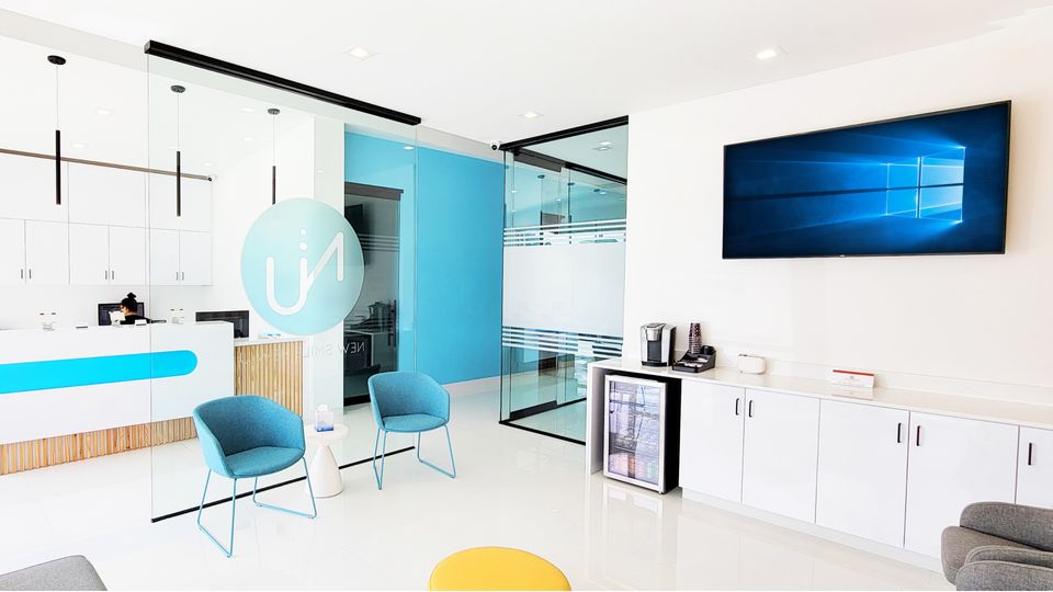 Modern dental office waiting room with blue chairs, reception desk, and glass partition walls