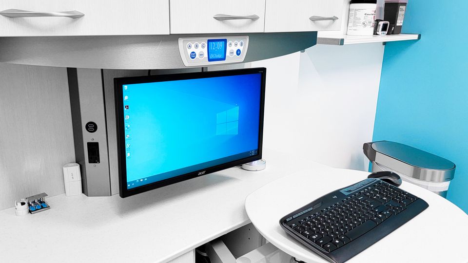 Modern dental treatment room workstation with mounted monitor and digital equipment